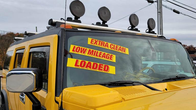 A used yellow Hummer with low mileage on a dealer lot.